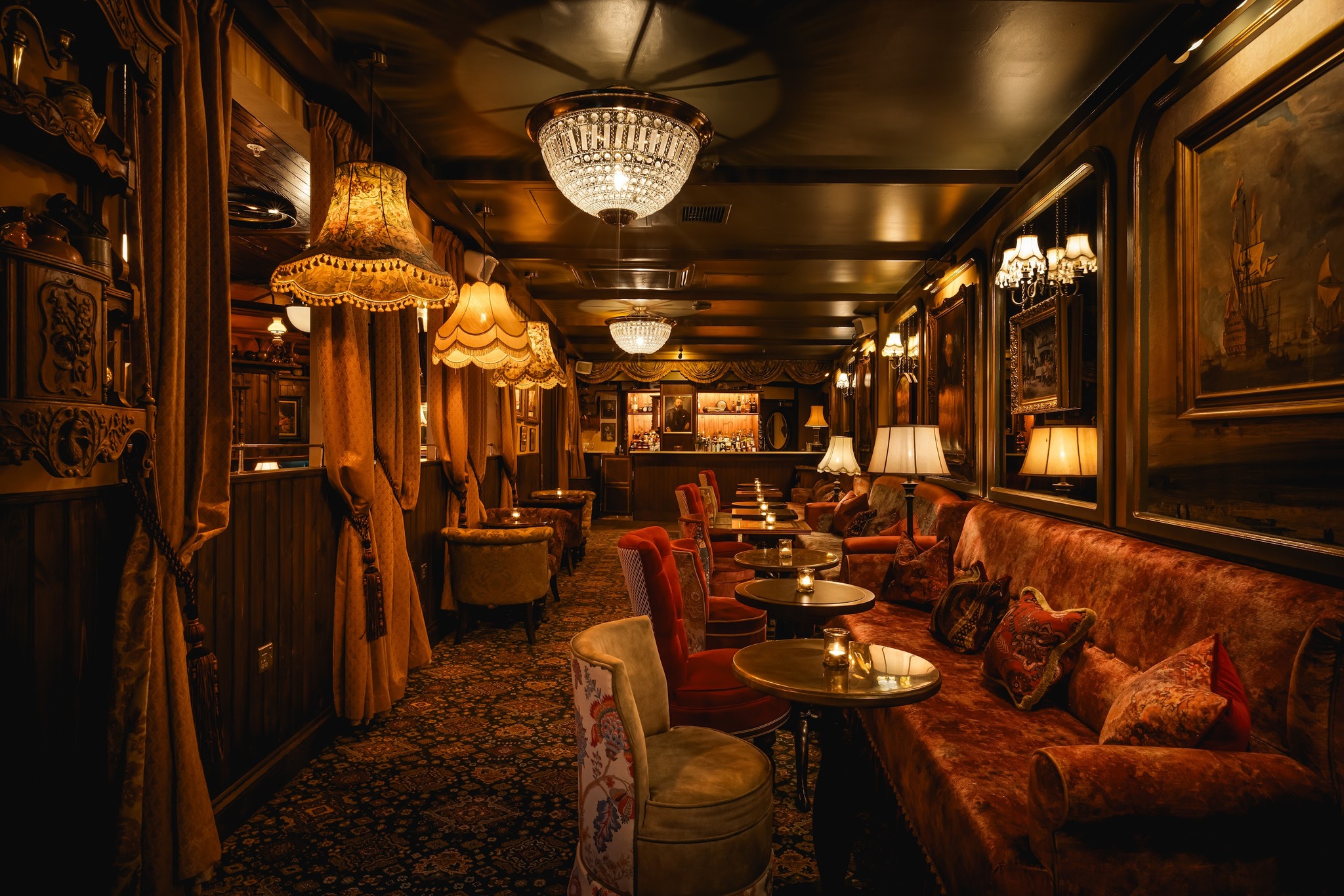 A plush restaurant bar area with low lighting and red velvet furniture.
