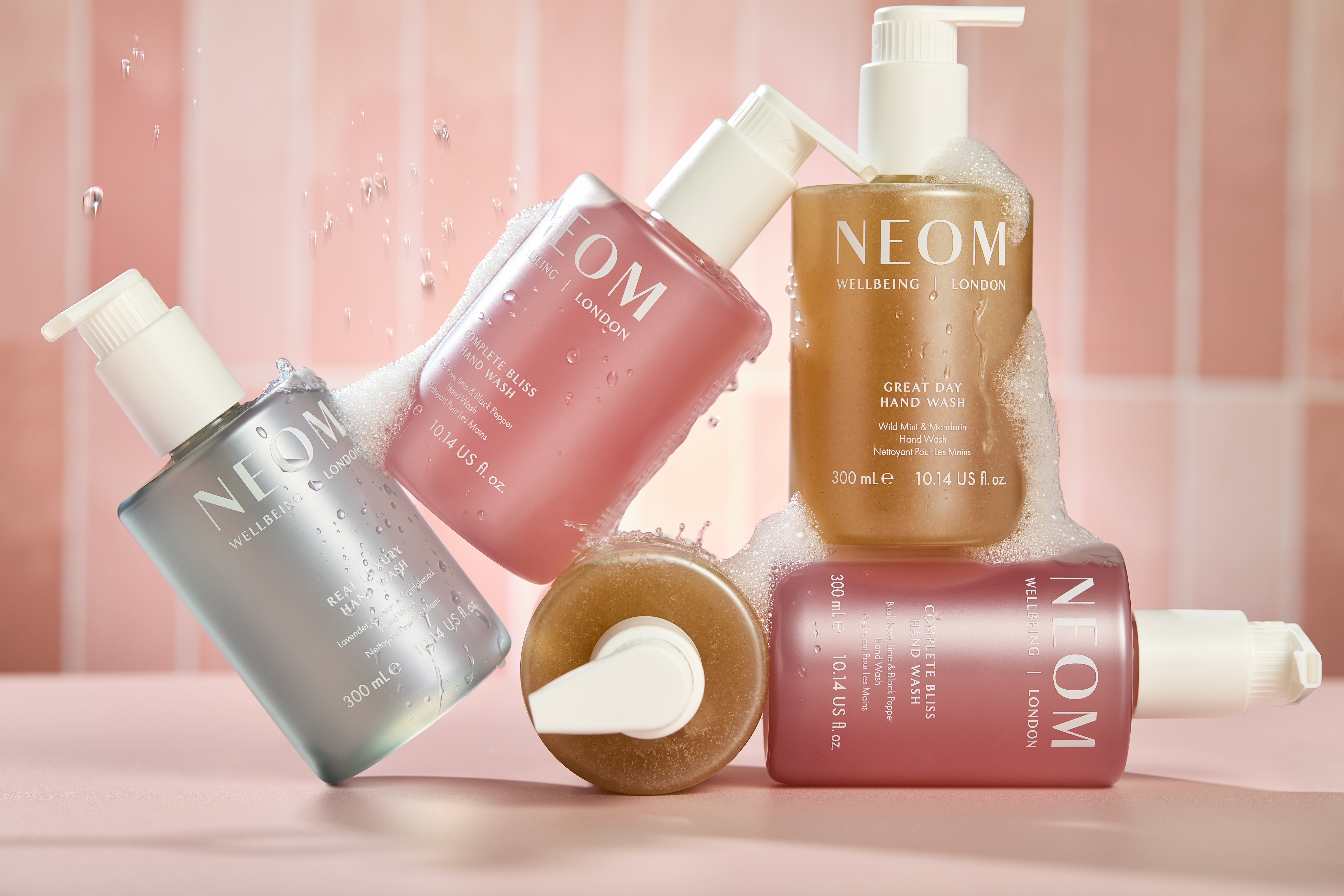 Several bottles of Neom handwash stacked against each other.
